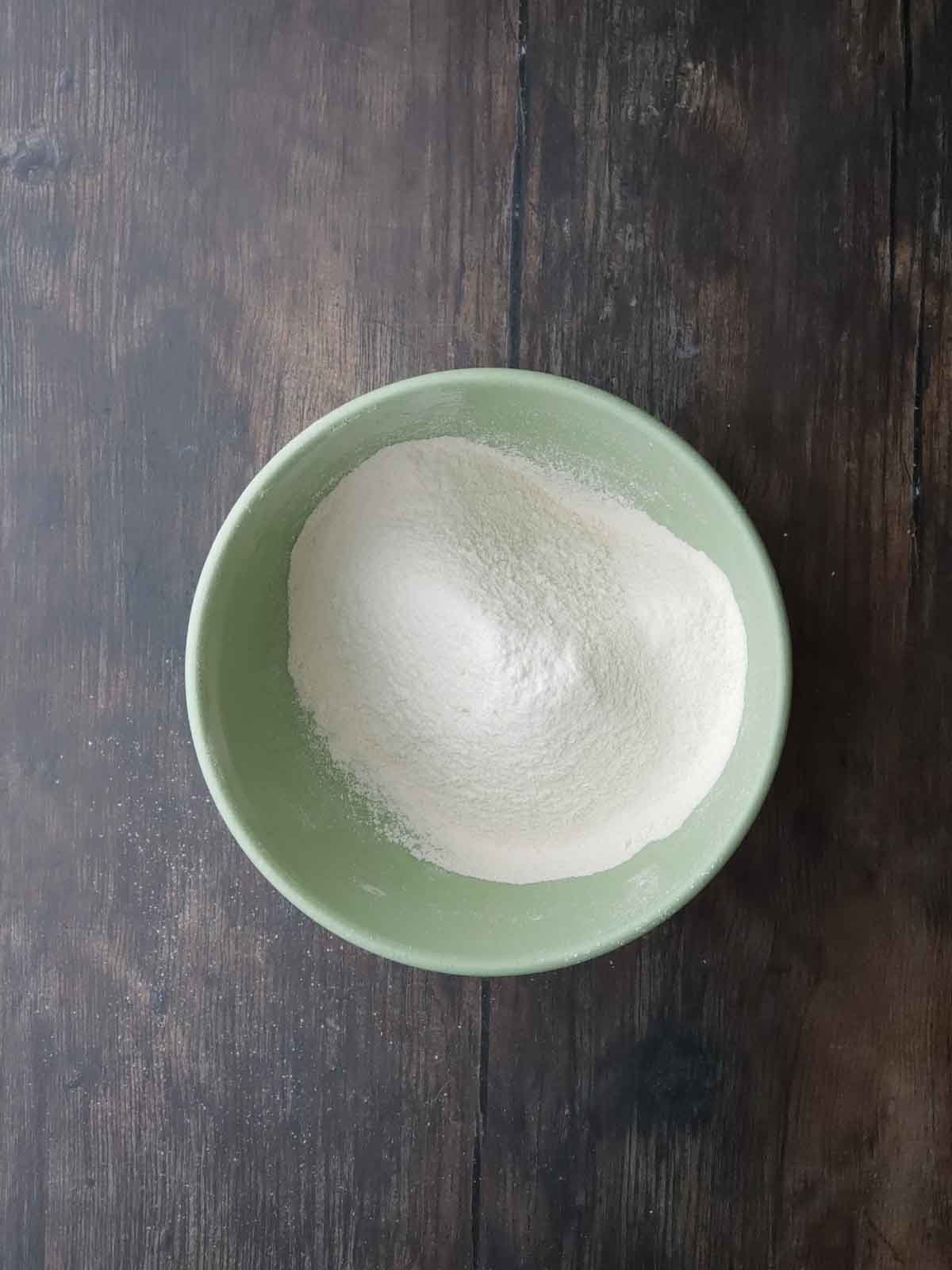Sifted flour in a green mixing bowl.