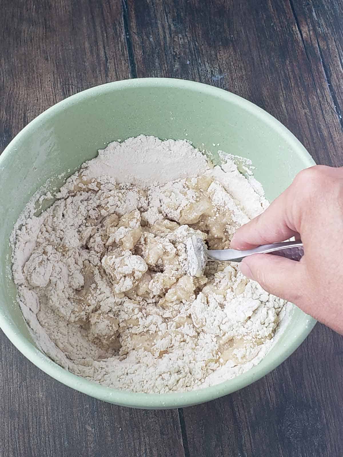 A fork combining the wet and dry ingredients in a mixing bowl for the dough.