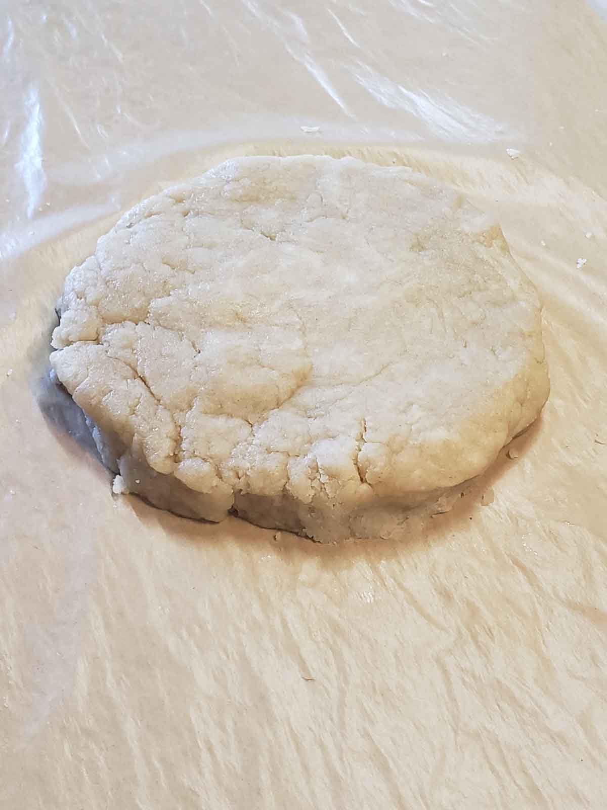 Shaping the dough into a flat circle about ¾ inch thick so it is ready for rolling out.