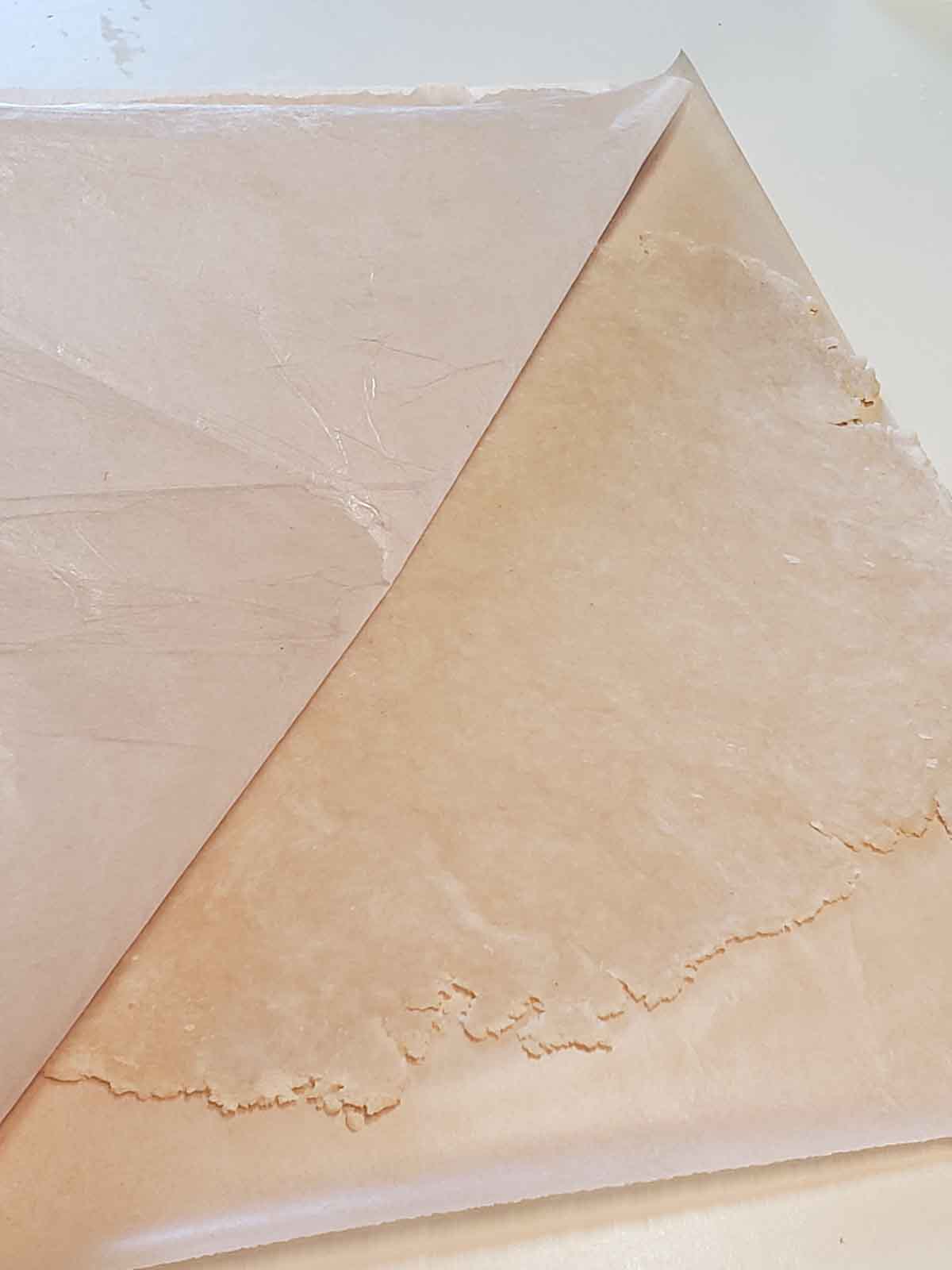 Peeling the wax paper off the crust to loosen it from the paper so it does not stick while placing it in the dish.