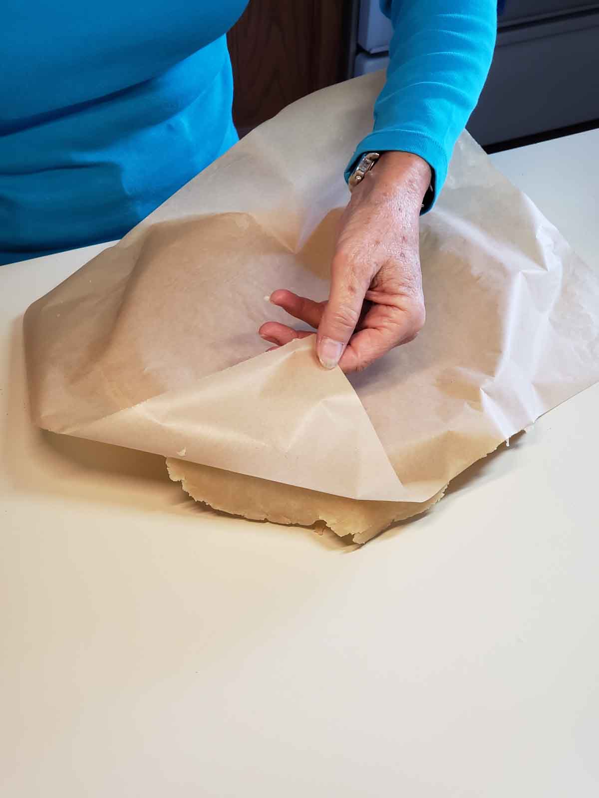 Removing the wax paper from the crust so it lays in the dish.