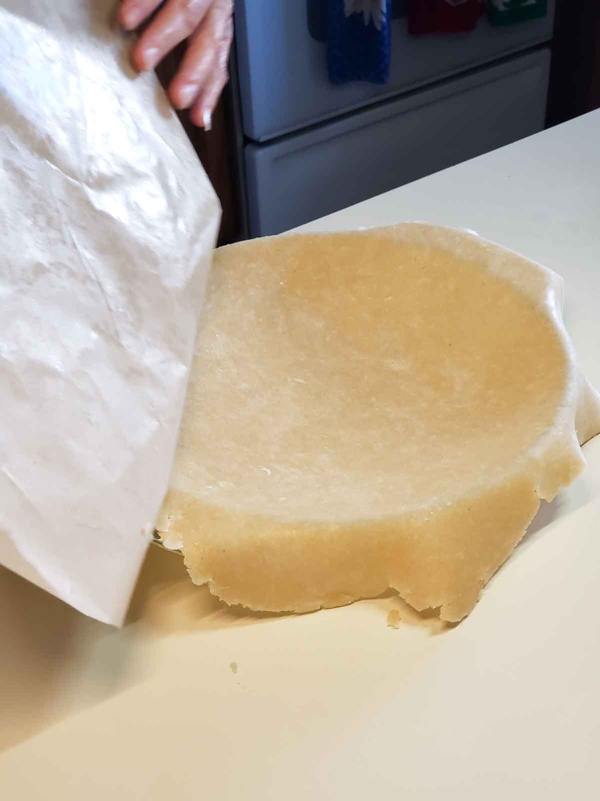 Taking the pie crust off of the wax paper and letting it fall gently into the pie dish.