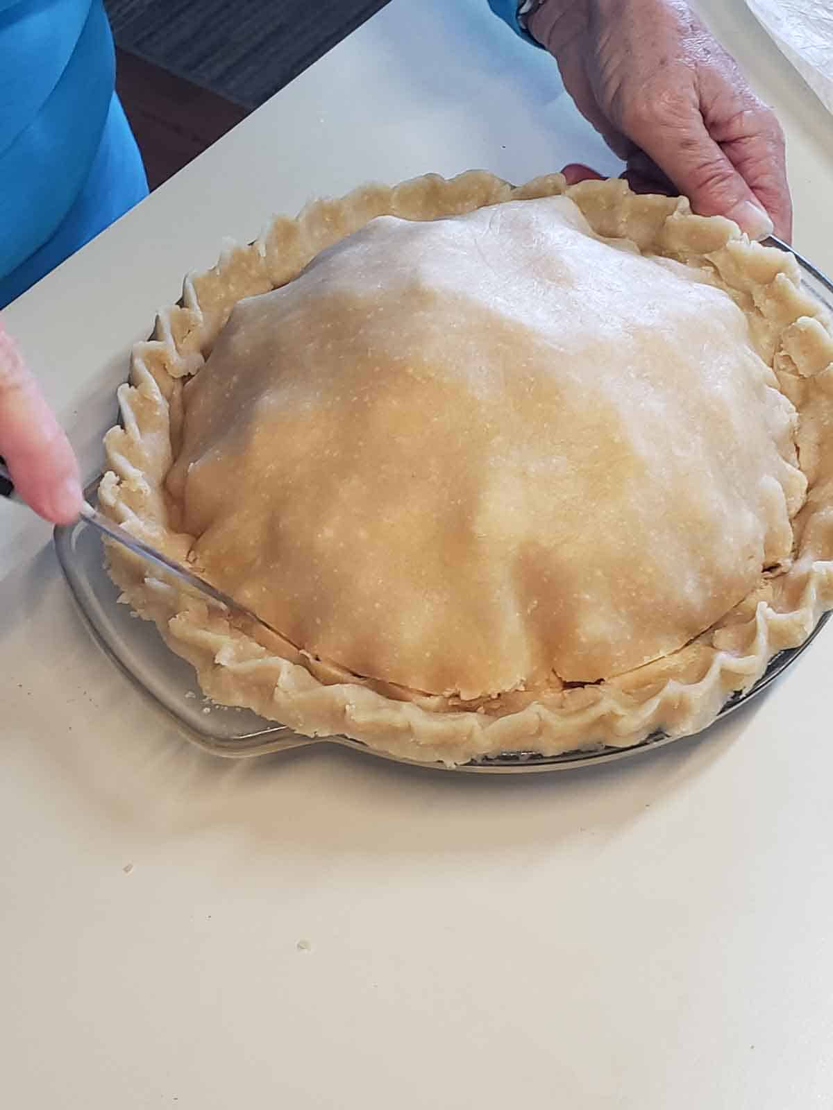Using a knife to make cuts in the crust for venting while baking.