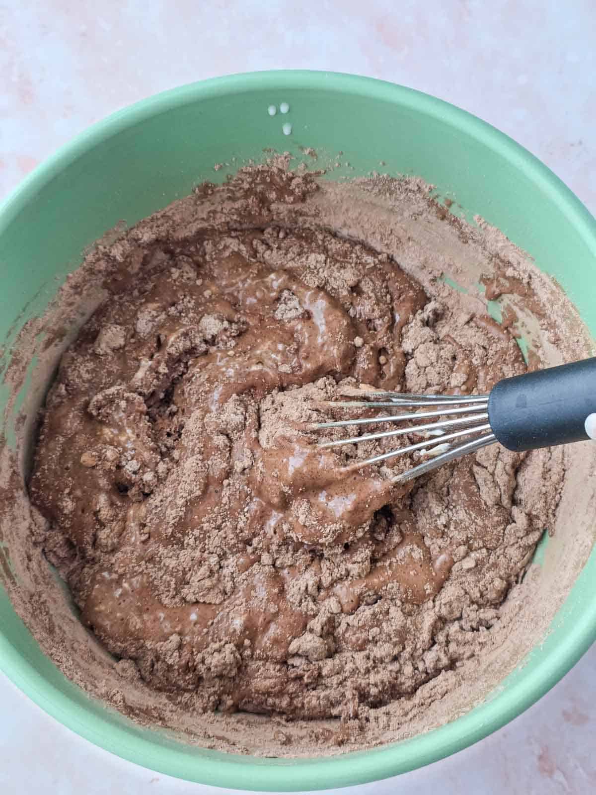 Whisk starting to combine the wet and dry ingredients in the bowl.