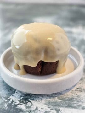 Chocolate cupcake covered in thick dairy-free cream cheese glaze dripping over the sides.
