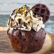 Chocolate cupcake topped with swirls of dairy-free cream cheese frosting and chocolate drizzle.