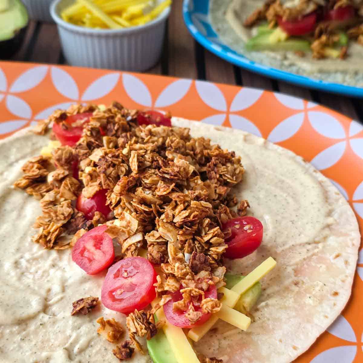 Detailed view of a vegan BLT wrap with coconut bacon, tomatoes, and cheese layered over avocado and ranch on a soft tortilla.