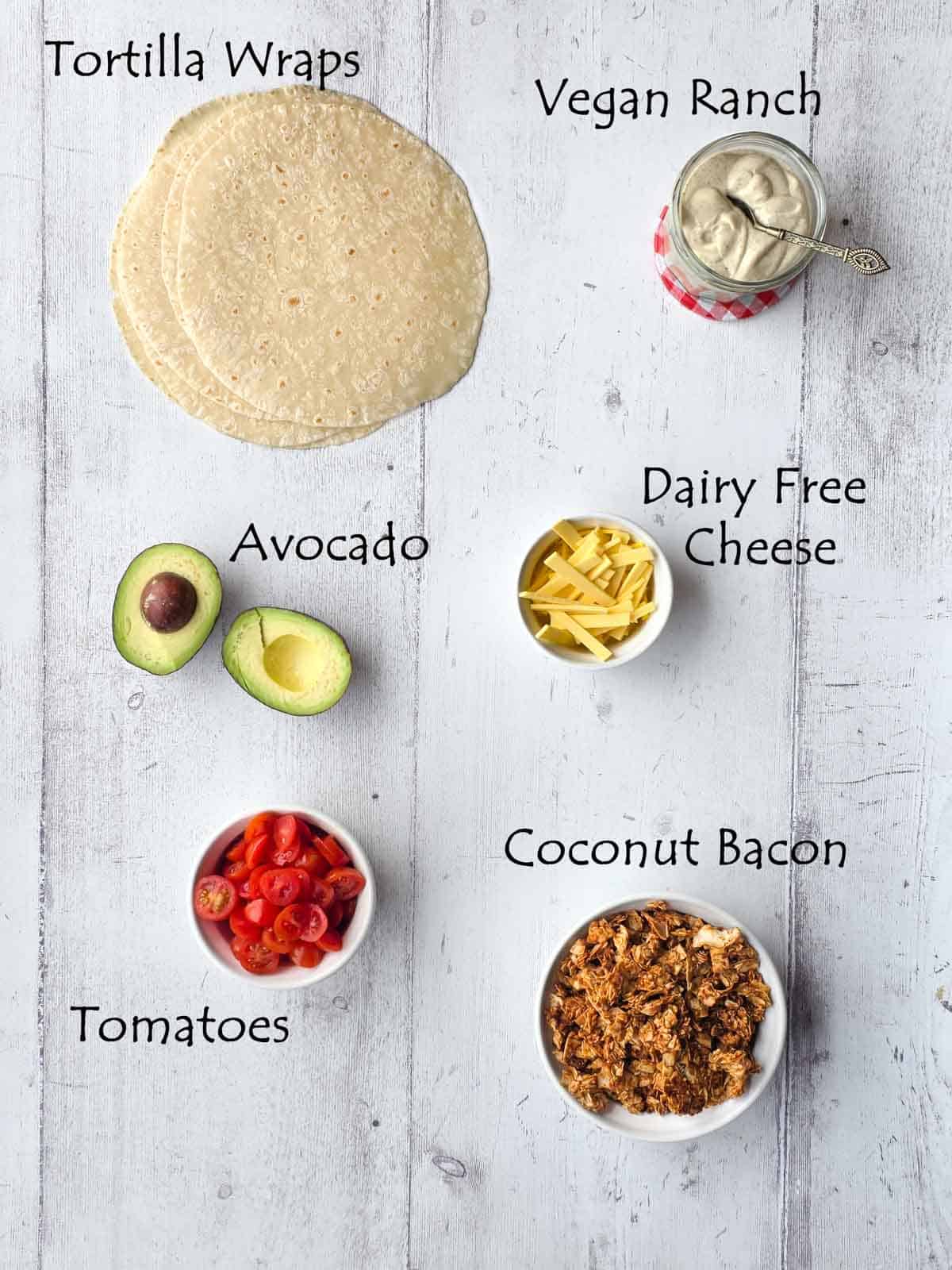 Plant-based BLT wrap ingredients including tortillas, avocado, tomatoes, dairy-free cheese, coconut bacon, and vegan ranch.