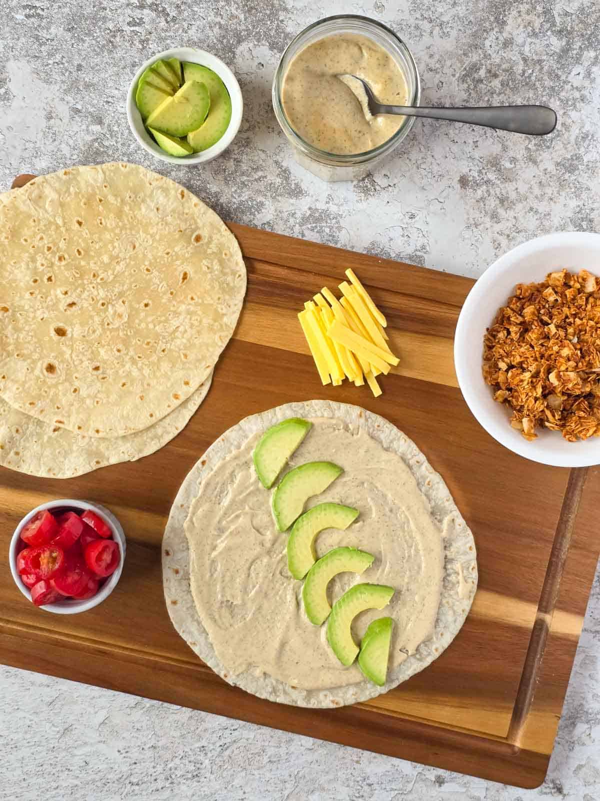 Sliced avocado layered over ranch on a soft tortilla wrap.
