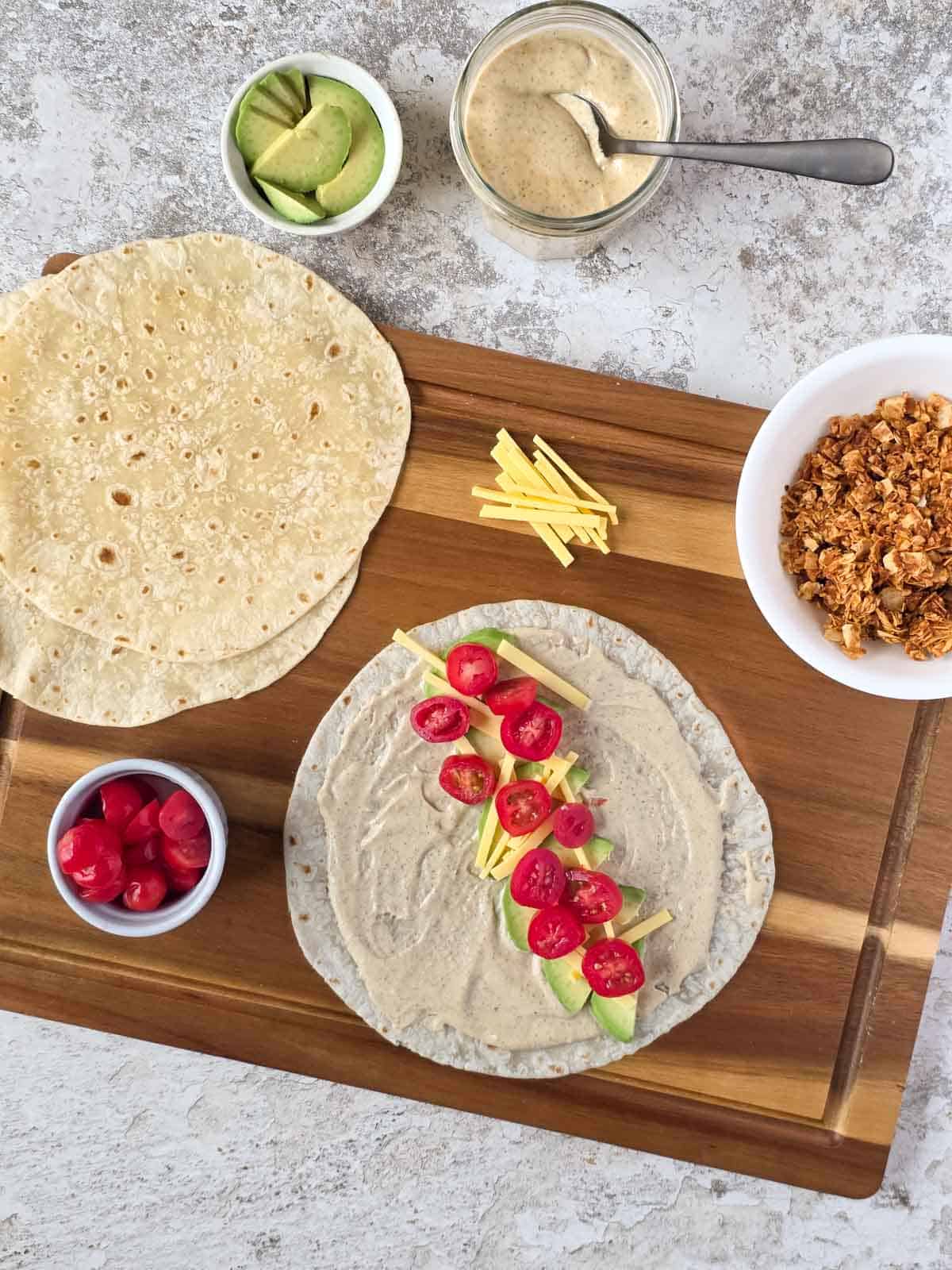 Cherry tomatoes layered over avocado and cheese on a prepared tortilla.