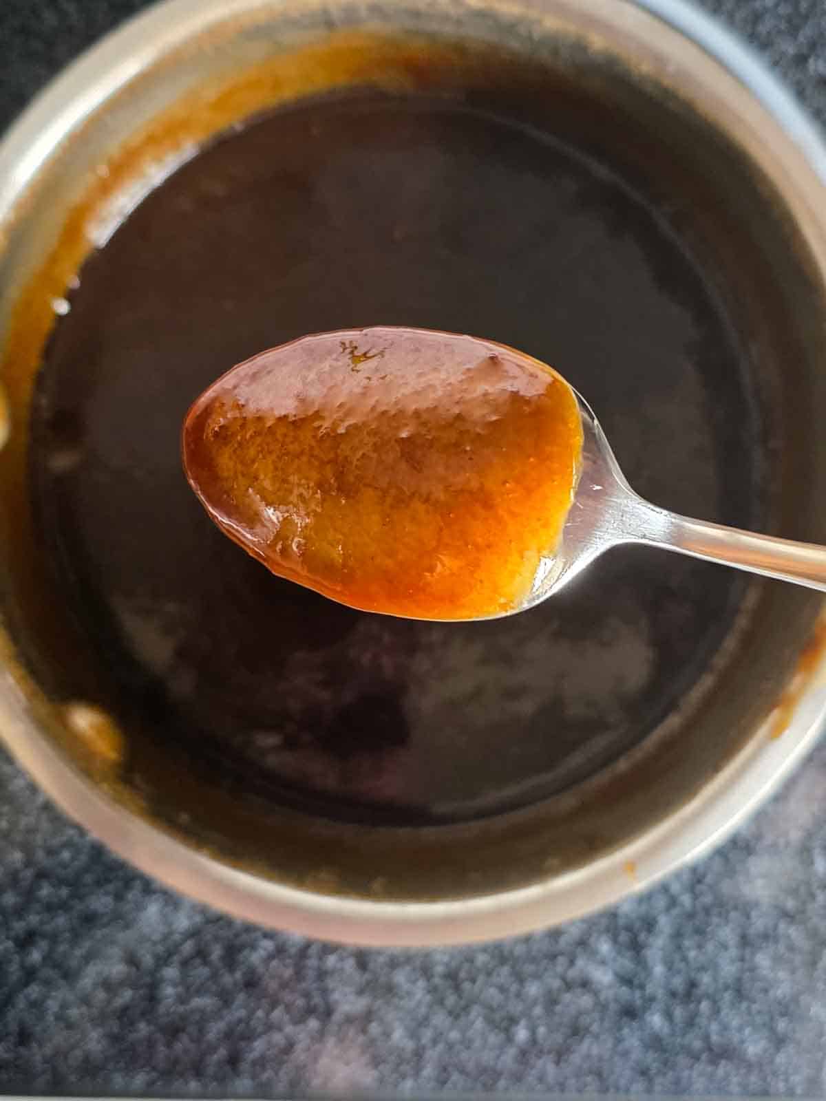 Caramel sauce coating the back of a spoon to show desired consistency.