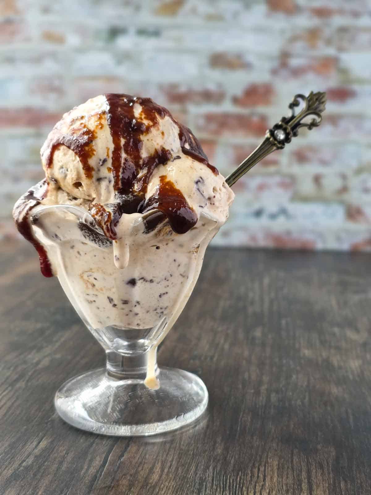 An ice cream sundae topped with vegan salted caramel sauce and a decorative spoon sticking out.