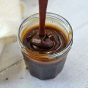 Thick, rich, vegan caramel sauce being dripped from a spoon to show texture.