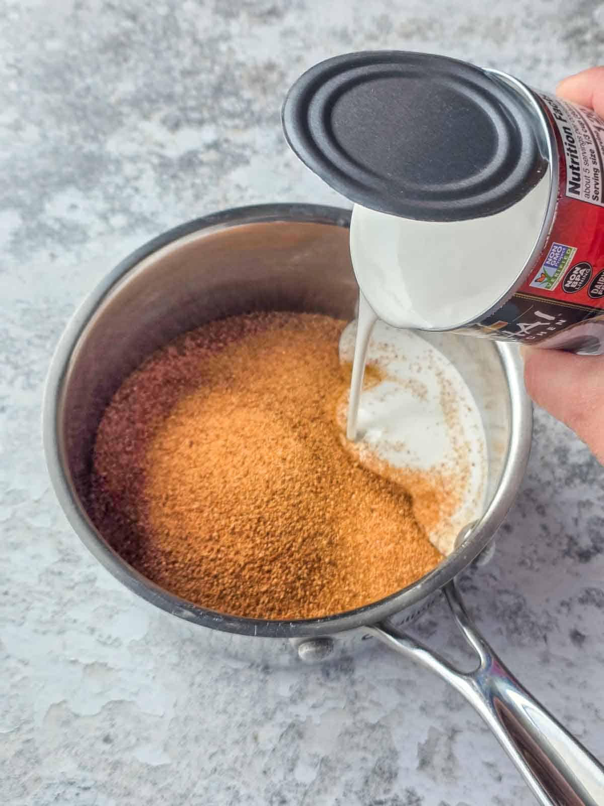A can of coconut milk being poured into a pan of coconut sugar to make caramel sauce.