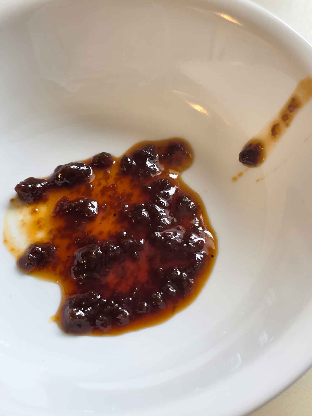 Caramel sauce that has separated being shown in a while bowl to show texture.