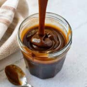Thick, rich, vegan caramel sauce being dripped from a spoon to show texture.
