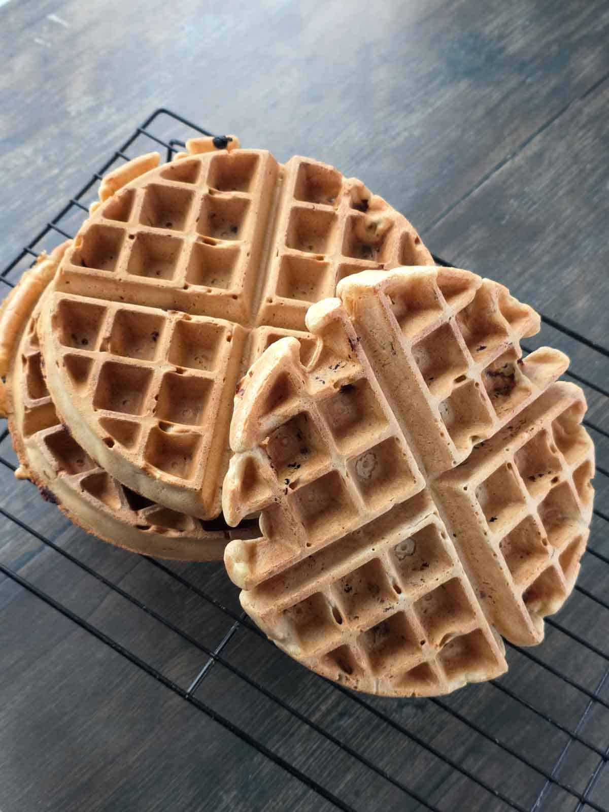 Homemade thick and fluffy waffles cooling on a rack after cooking.