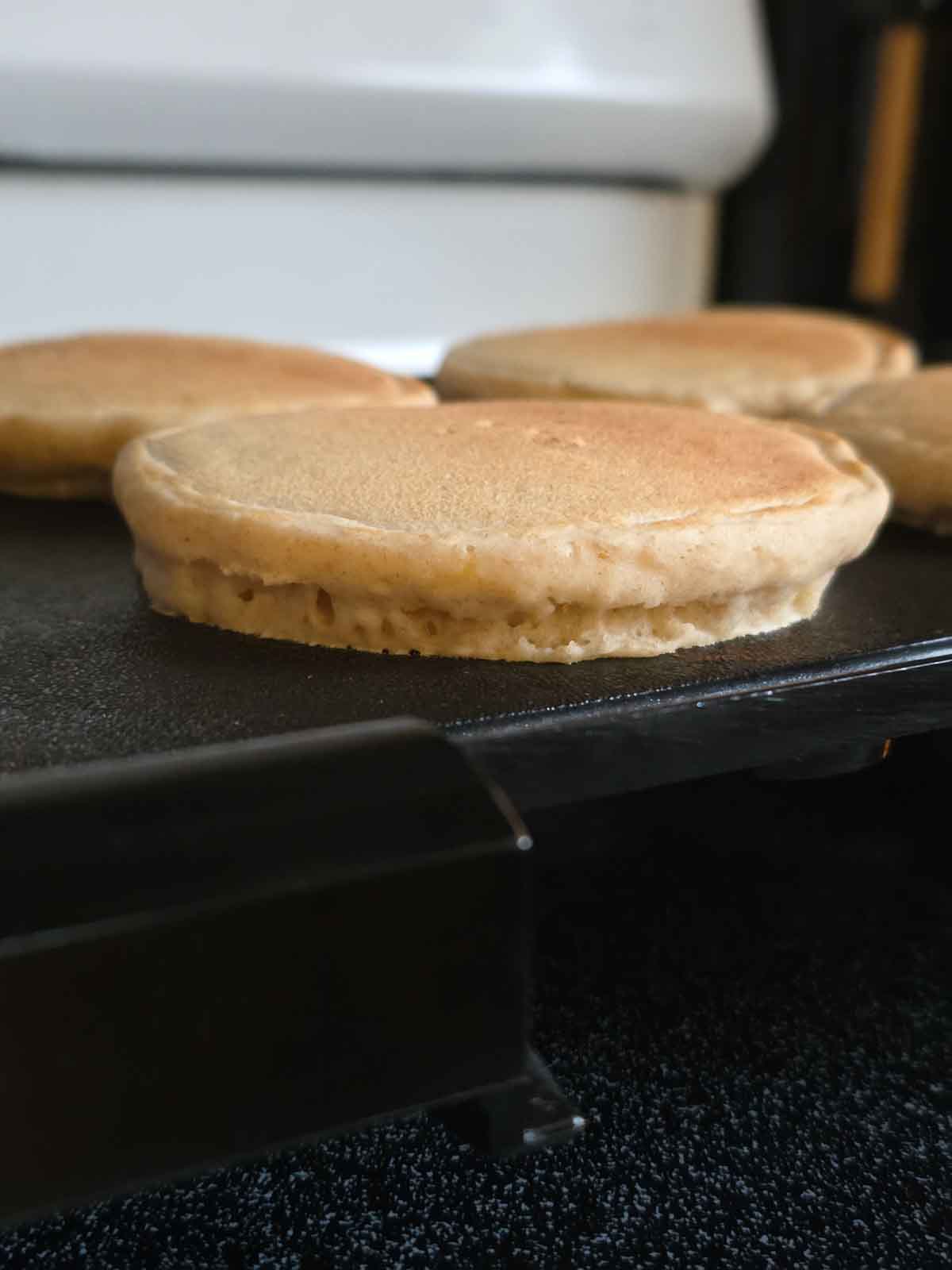 Pancakes cooking on a griddle showing fluffy side texture.