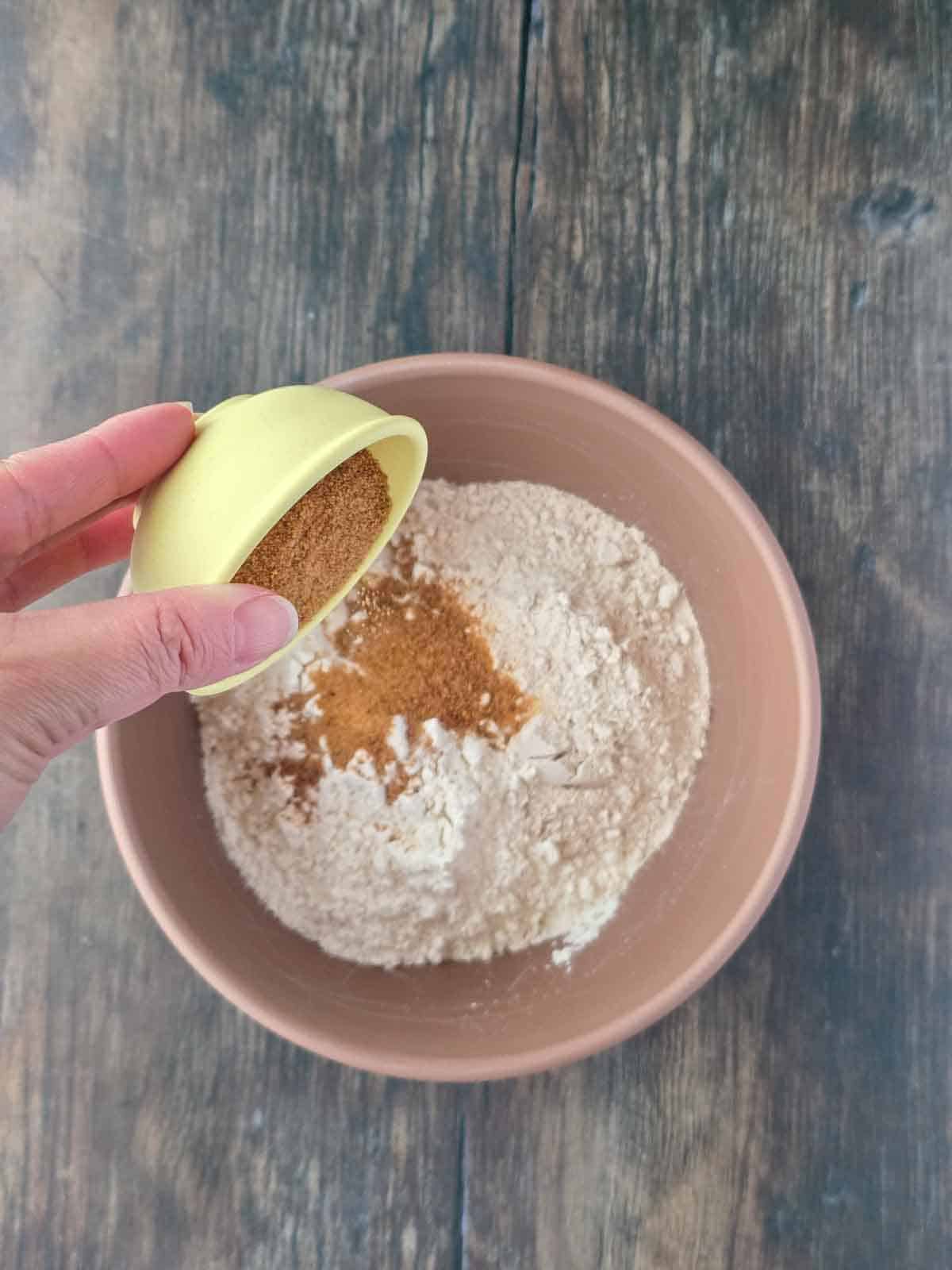 Adding coconut sugar to the dry pancake ingredients in a mixing bowl.