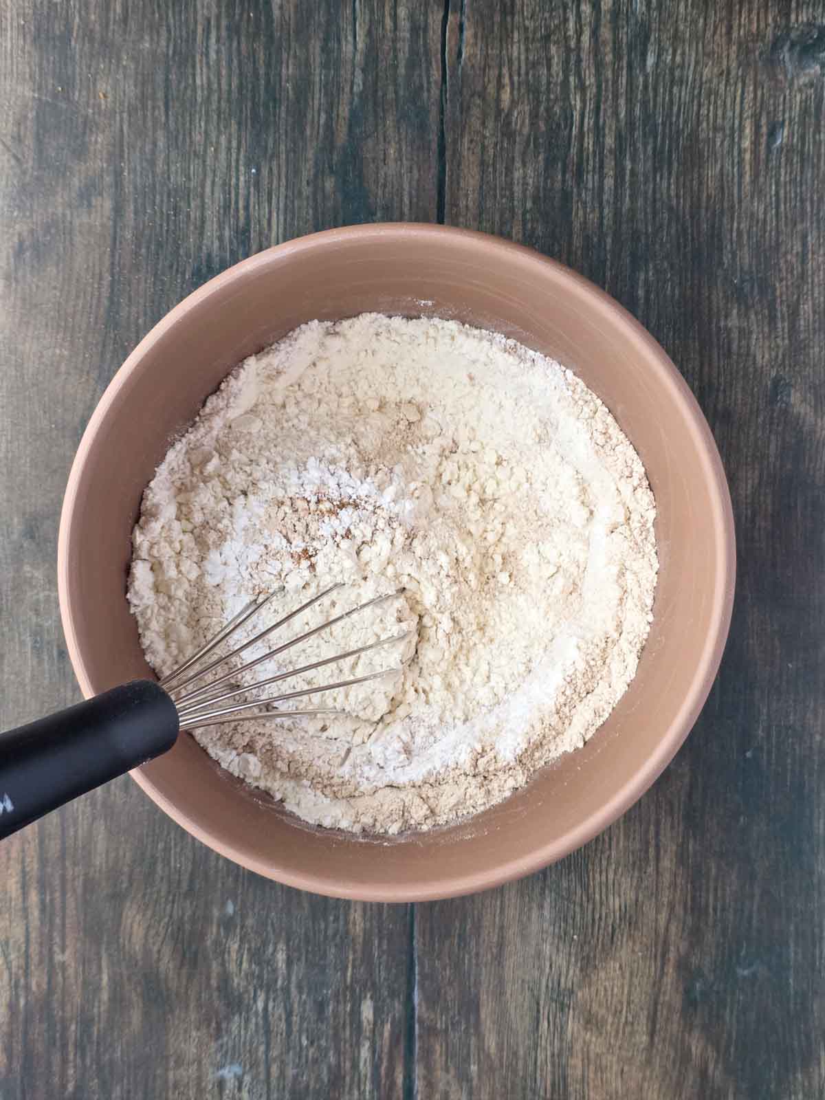 Whisk resting in a bowl of dry ingredients for pancakes.
