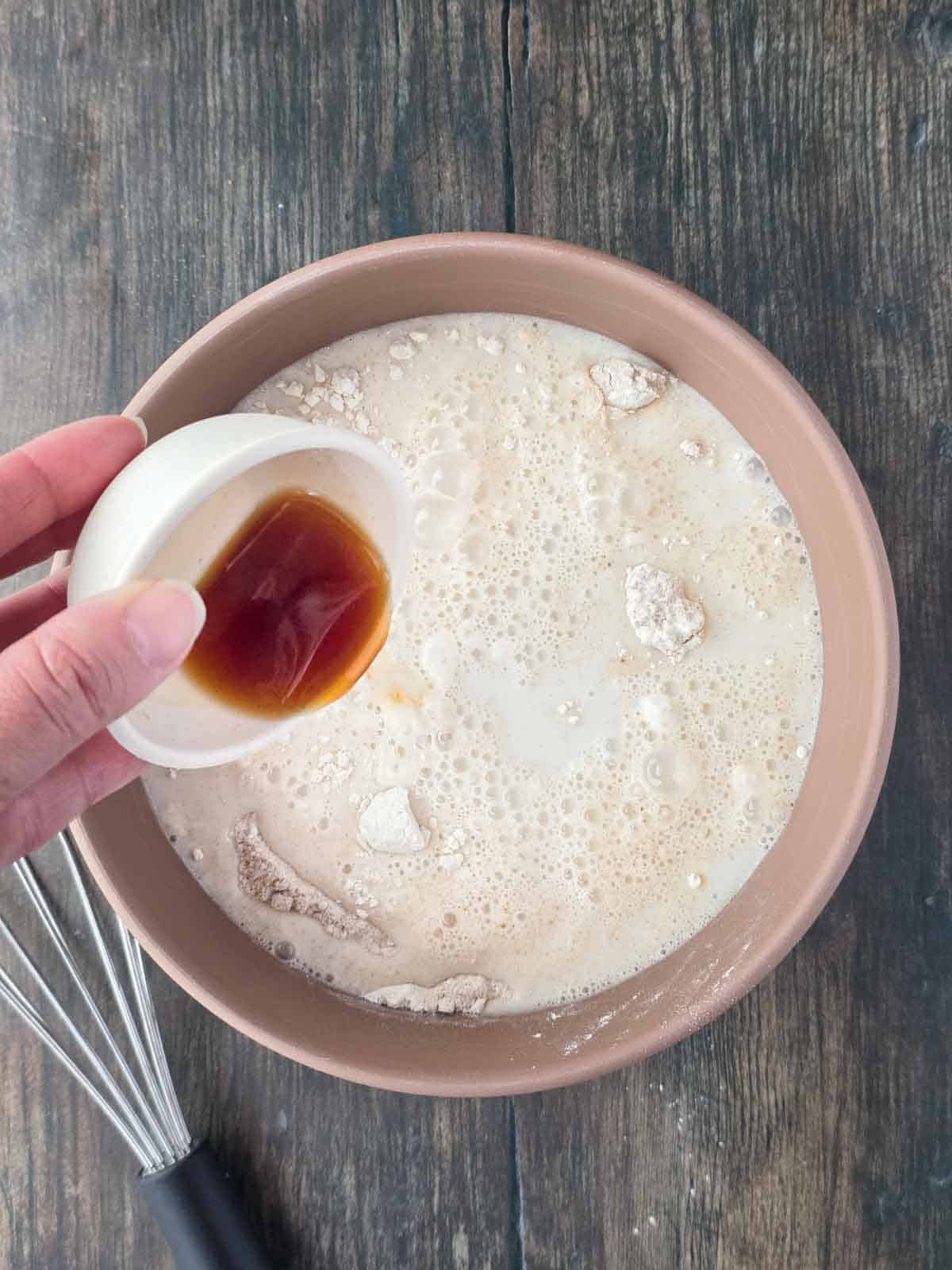 Adding vanilla extract to the pancake batter.