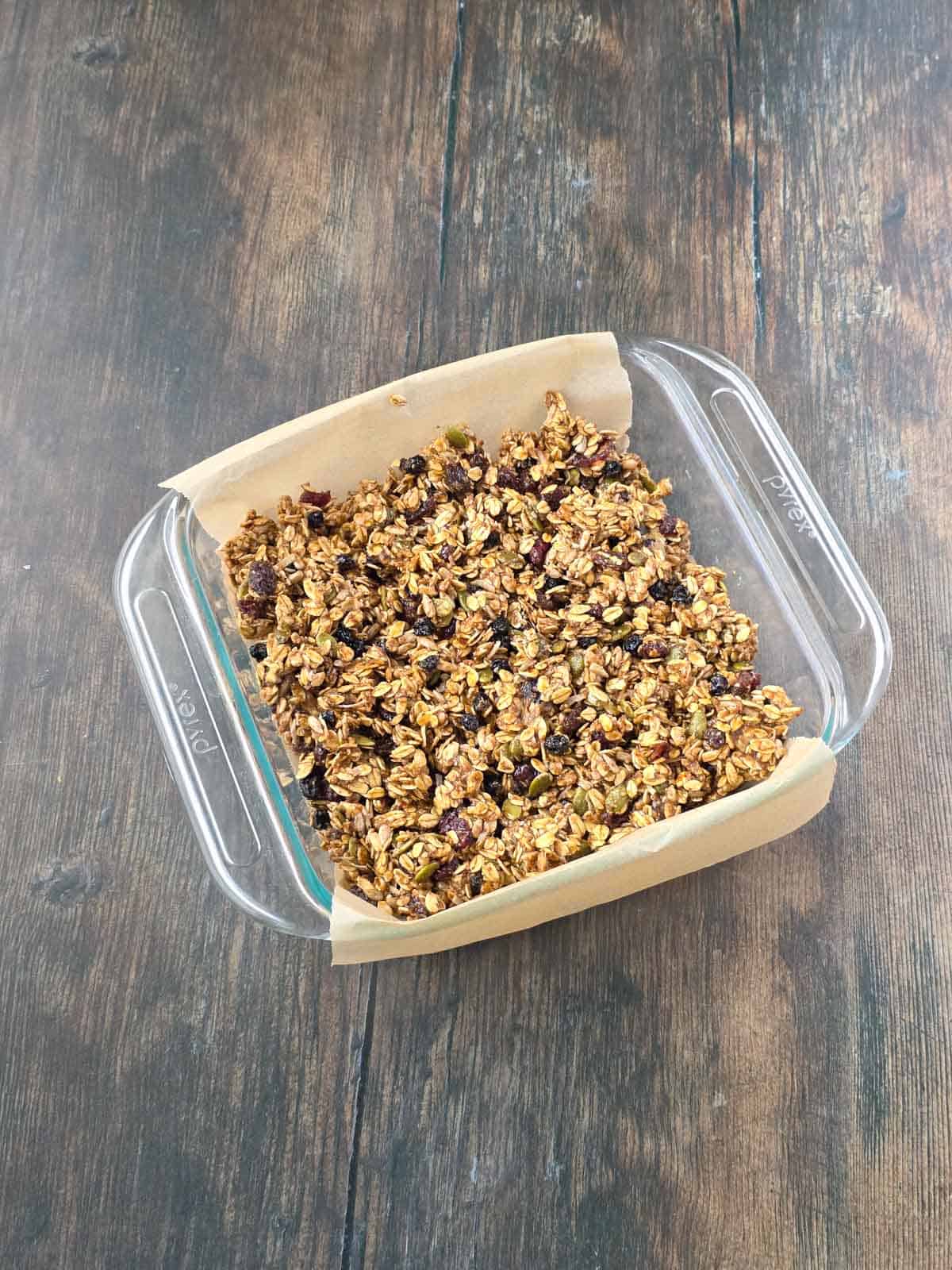 Granola bar mixture spread evenly across the baking dish.