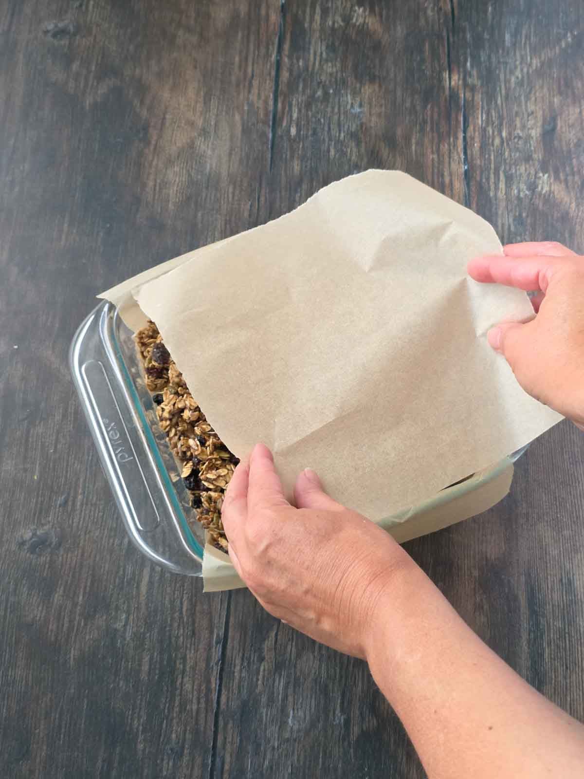 Placing a sheet of parchment paper over the granola bar mixture.