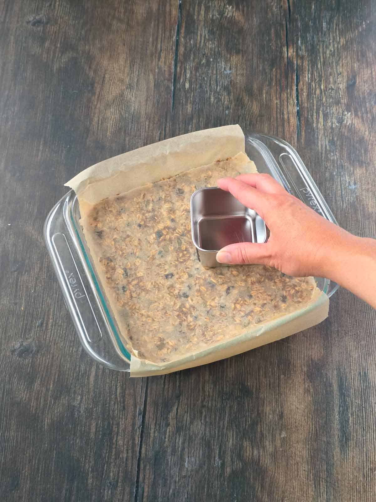 Pressing the granola bar mixture firmly and evenly into the corners and edges of the pan.