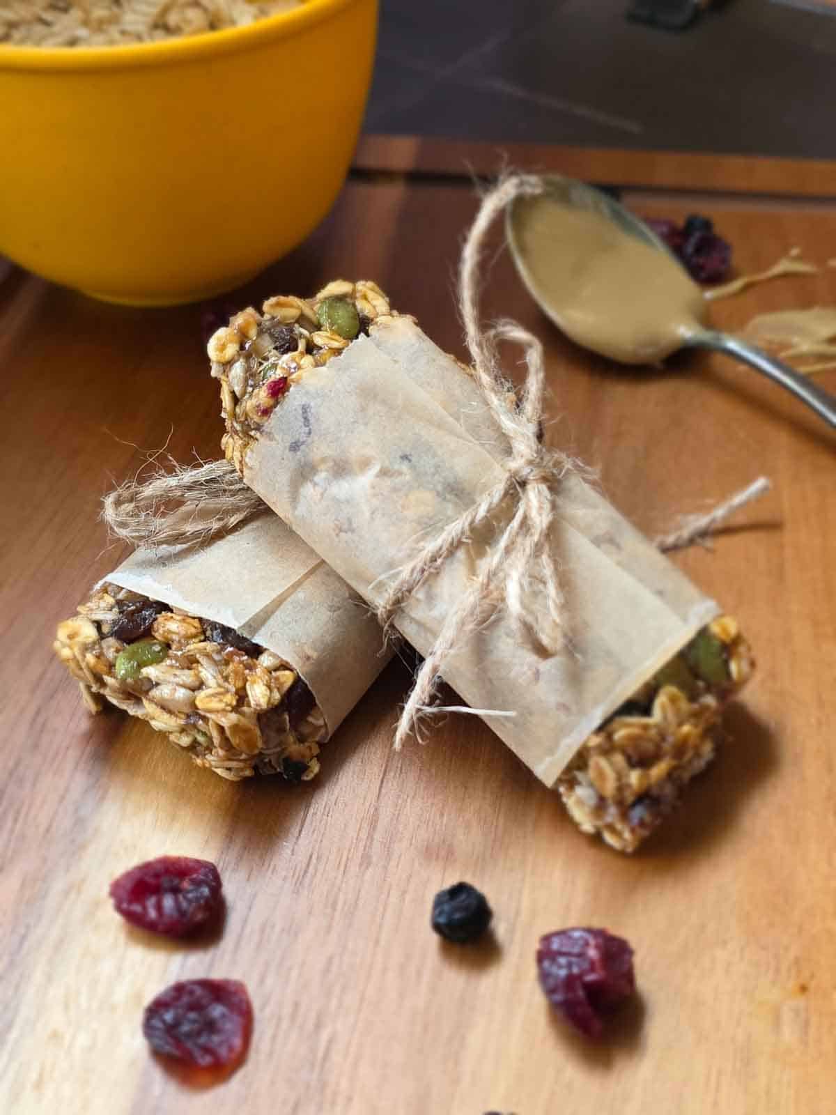 Chewy triple berry granola bars wrapped in parchment with oats, seeds and dried berries visible.