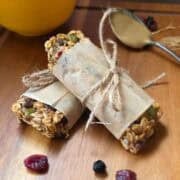 Chewy triple berry granola bars wrapped in parchment with oats, seeds and dried berries visible.