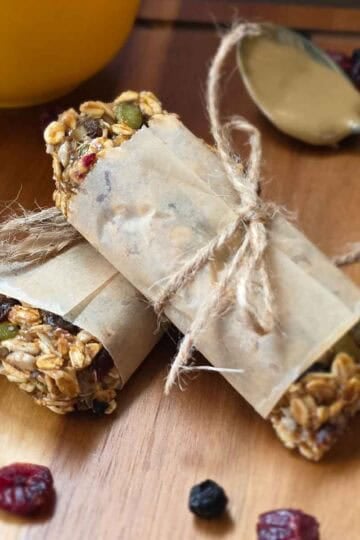 Chewy triple berry granola bars wrapped in parchment with oats, seeds and dried berries visible.