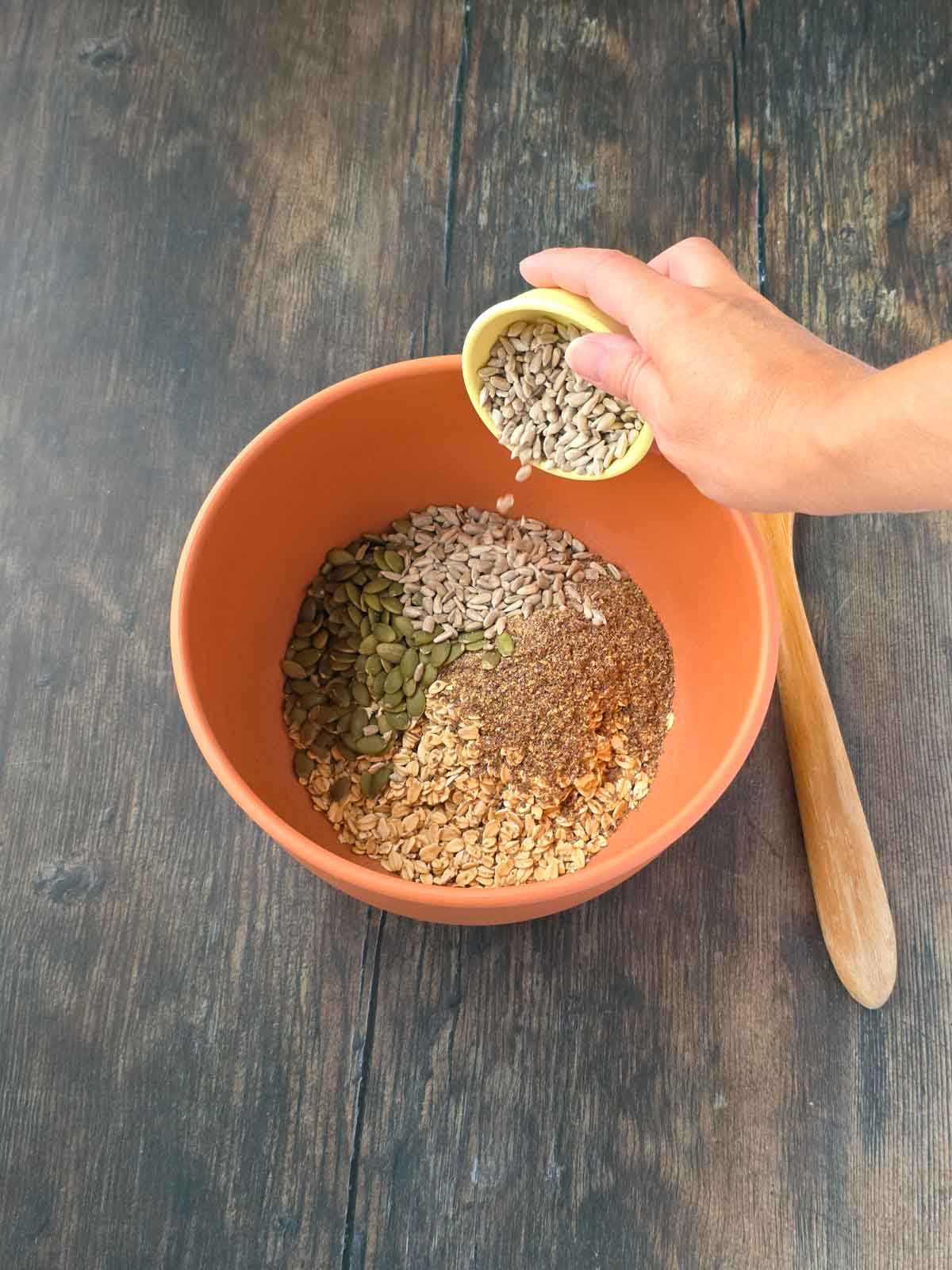 Adding raw sunflower seeds to the granola bar mixture.